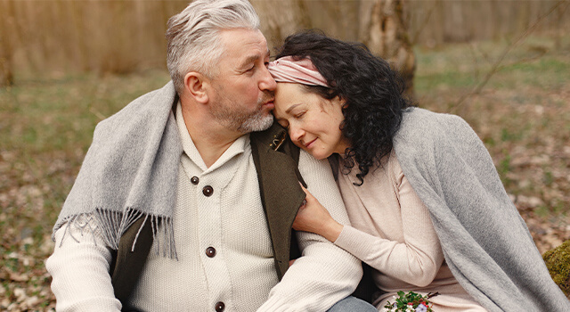 elderly couple sitting outside width=